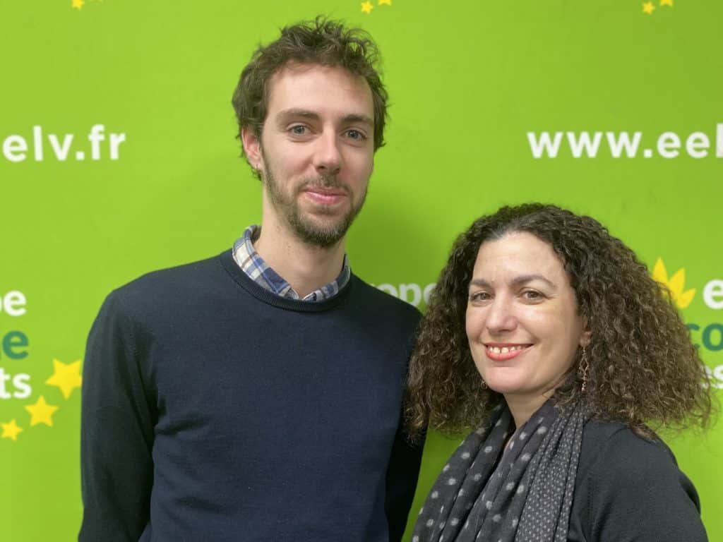 Léo Bousquet, un grand jeune homme, et Zineb Tazi, une femme à l'air serein, sourient devant un fond vert et jaune, aux couleurs d'EELV. Ce sont les responsables du pôle "mobilisations et relations extérieures" du BED de EELV Paris.